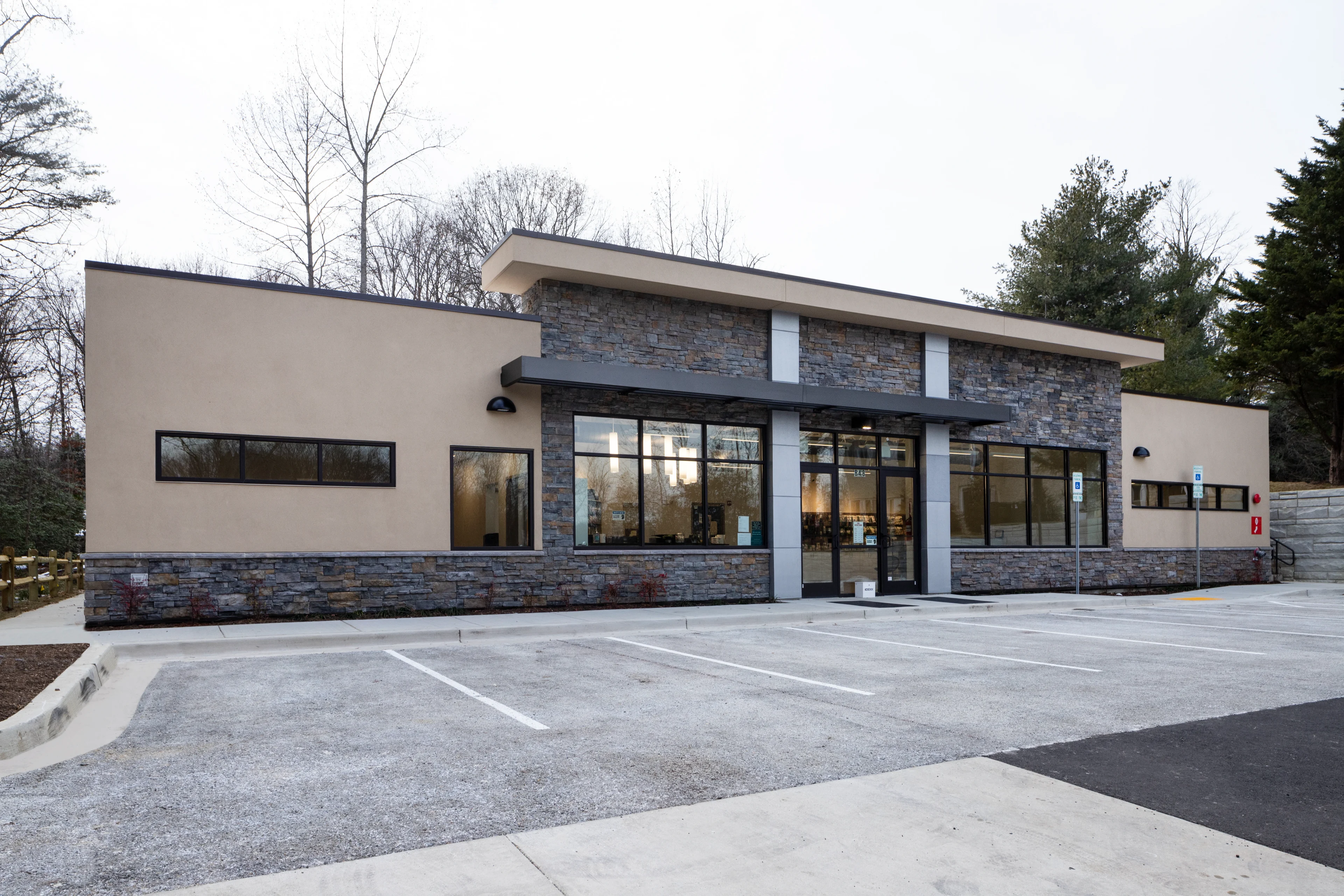Modern building with large windows and parking lot.