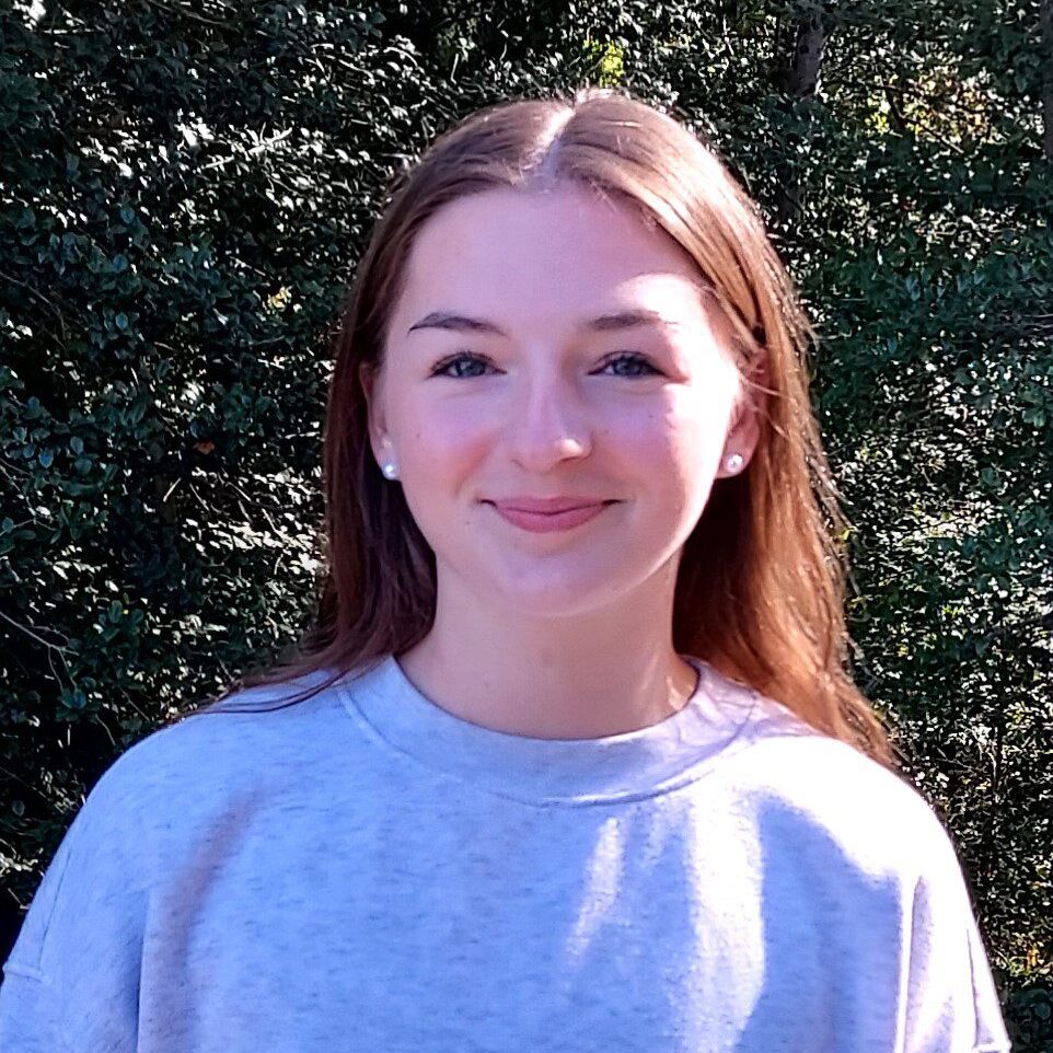 Smiling young woman outdoors against leafy background